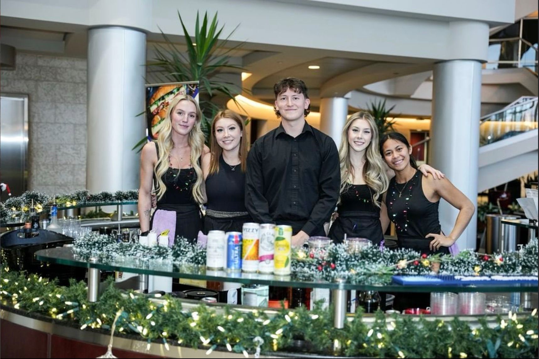 The Bold & Boozy team behind a bar dressed with garland and lights